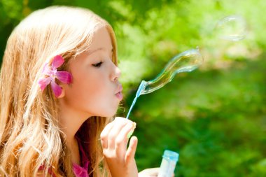 Children blowing soap bubbles in outdoor forest clipart