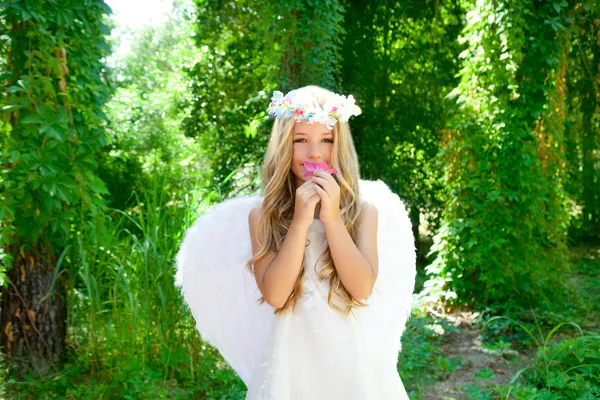 Девочка-ангел, нюхающая розовый цветок в лесу — стоковое фото