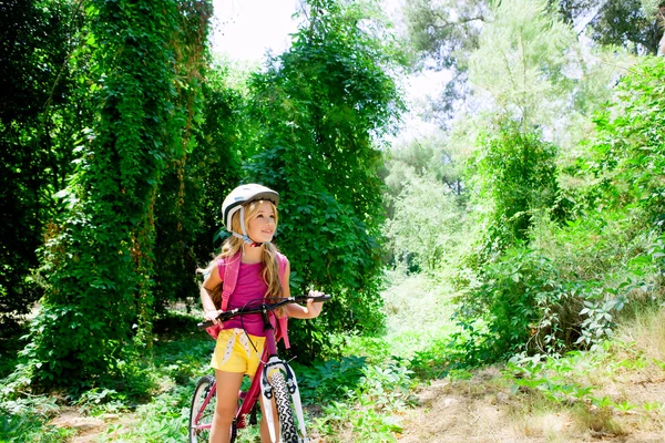 Barn tjej ridning cykel utomhus i skogen leende — Stockfoto