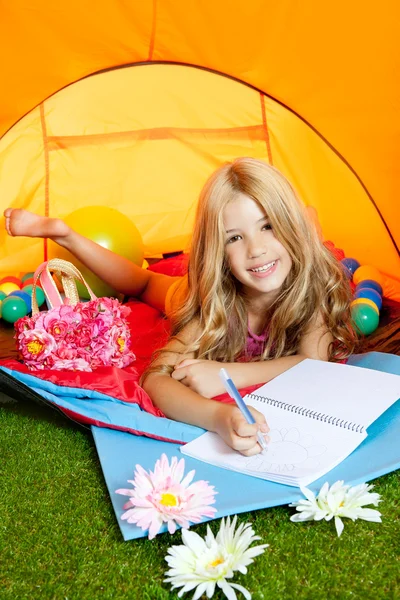 Bambini ragazza scrittura taccuino in tenda da campeggio con fiori — Foto Stock