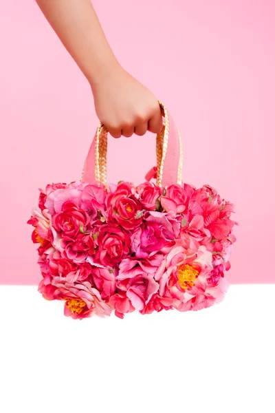 Röda blommor väska i kvinna hand på rosa bakgrund — Stockfoto