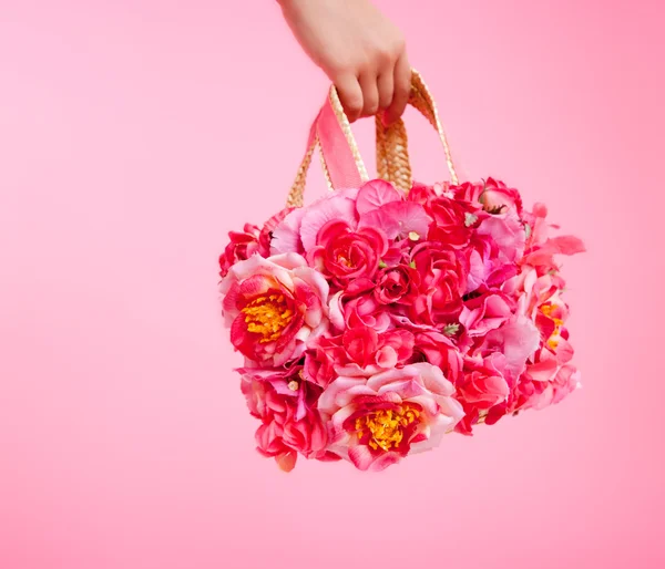 Röda blommor väska i kvinna hand på rosa bakgrund — Stockfoto