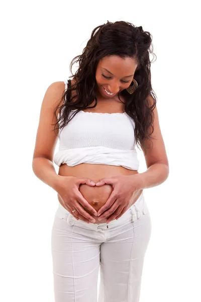 Kobieta trzyma ręce w kształcie serca, na jej ciąży — Zdjęcie stockowe