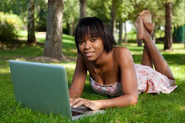 Retrato ao ar livre de jovem mulher negra usando um laptop — Fotografia de Stock