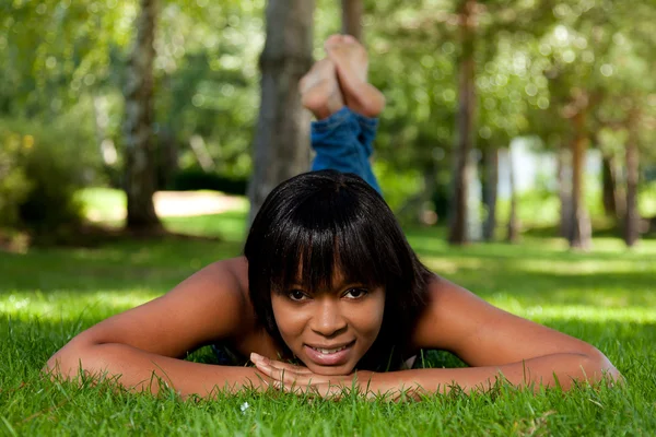 Jovem mulher negra deitada na grama — Fotografia de Stock