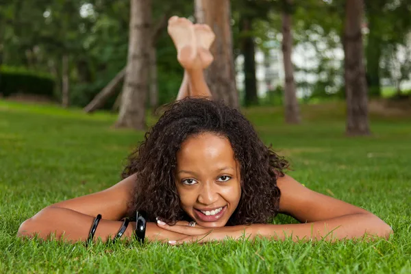 Молода чорна жінка лежить на траві — стокове фото