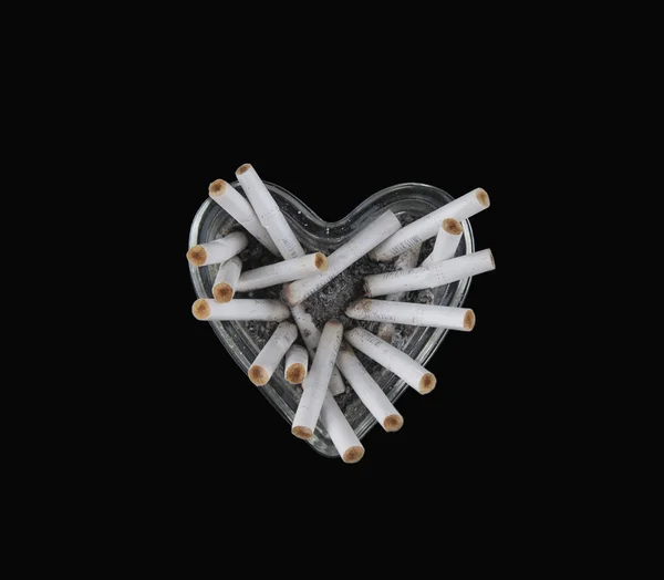 Corazón de cristal con colillas de cigarrillo sobre un fondo blanco — Foto de Stock