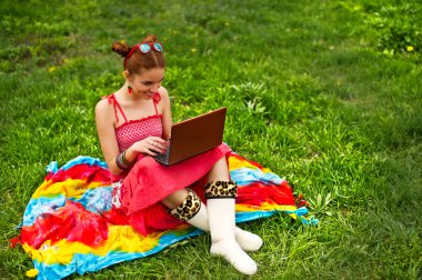 Yeşil çimenlerin üzerinde laptop ile güzel bir genç kadın