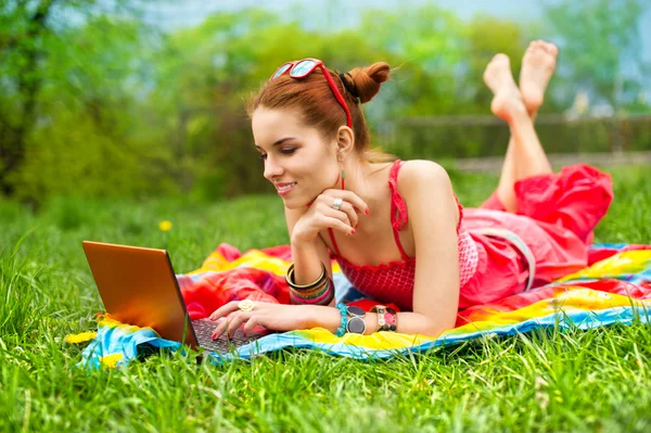 Yeşil çimenlerin üzerinde laptop ile güzel bir genç kadın — Stok fotoğraf