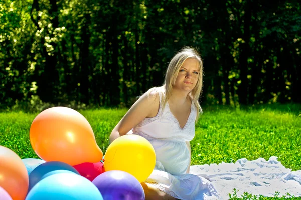 Pregnant woman sitting in colorful baloons — Stock Photo, Image
