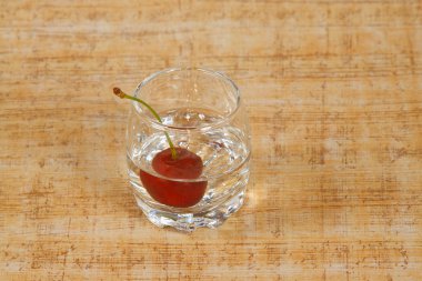 The glass of beverage and cherry