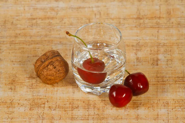 El vaso de bebida, cereza y nueces — Foto de Stock