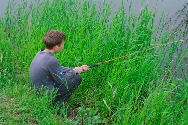 Il giovane pescatore con la verga al fiume — Foto Stock