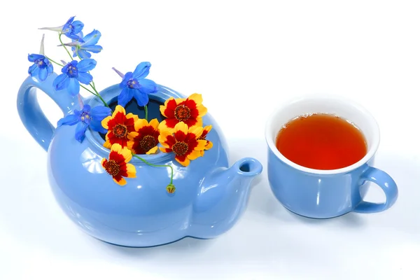 Синій чайник з квітами і чашкою чаю — стокове фото