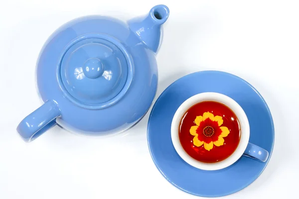 Голубой чайник и чашка чая с цветами — стоковое фото