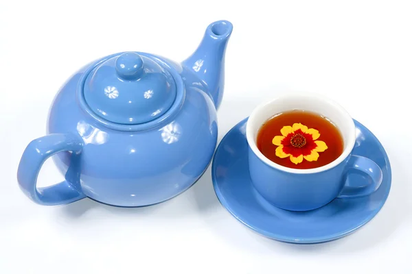 Modrá konvice a šálek čaje s květinami — Stock fotografie