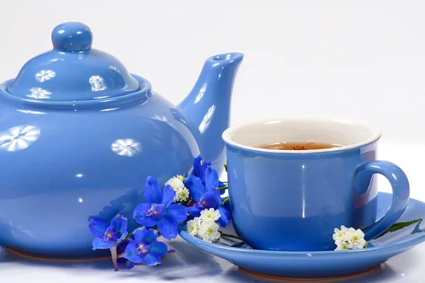 Den blå kedel og kop te med blomster - Stock-foto