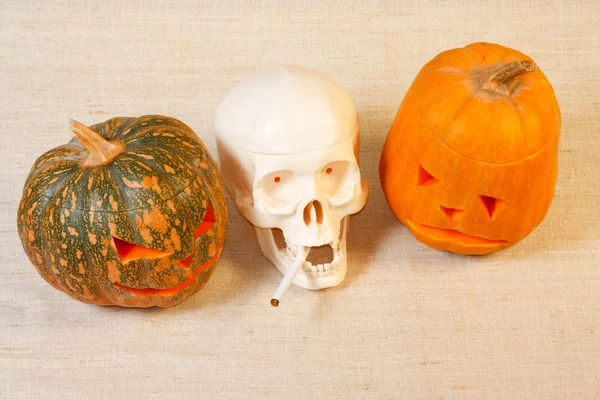 The cheerful and sad halloween pumpkin and skull with cigarette — Stock Photo, Image