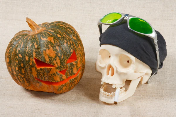 The big cheerful halloween pumpkin and skull with sigarette — Stock Photo, Image