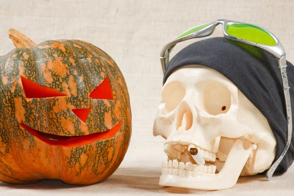 The big cheerful halloween pumpkin and skull with sigarette — Stock Photo, Image