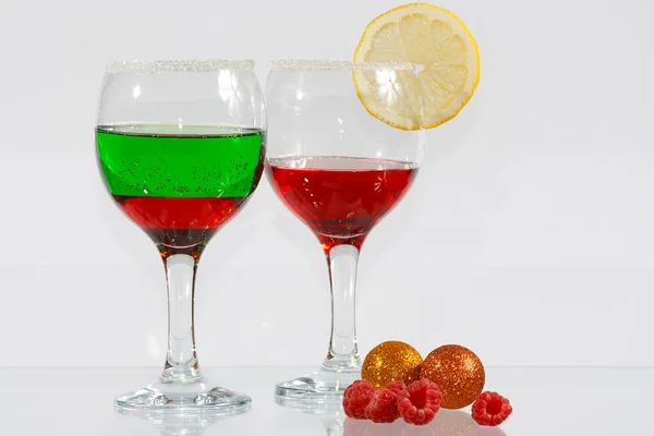 Die zwei Gläser mit rotem und grünem Schnaps, Zitrone und Himbeeren — Stockfoto