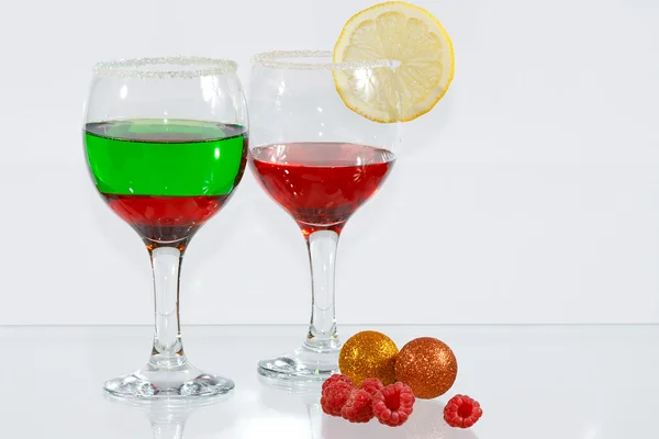 The two glasses of red and green liquor, lemon and raspberries — Stock Photo, Image