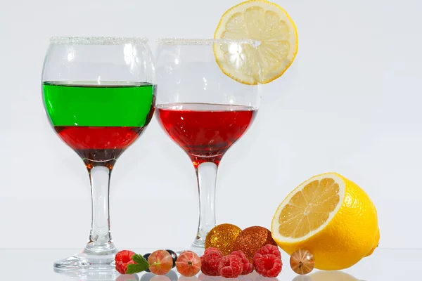 The two glasses of red and green liquor, lemon and berries — Stock Photo, Image
