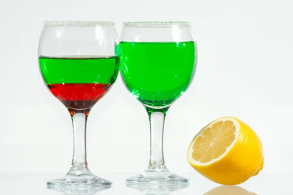 The two glasses of green and red liquor and lemon — Stock Photo, Image