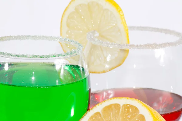 The two glasses of green lemonade, red liquor and lemon — Stock Photo, Image