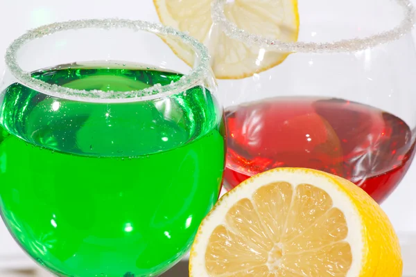 A két pohár limonádé zöld, vörös folyadék és citrom — Stock Fotó