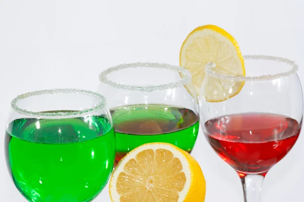 Три стакана зеленого лимонада, красного ликера и лимона — стоковое фото