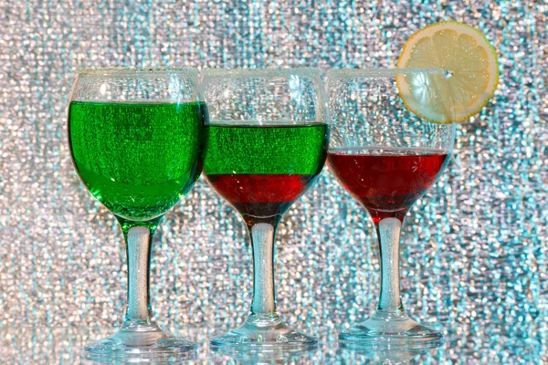 Die drei Gläser grünen und roten Schnaps und Zitrone lizenzfreie Stockfotos