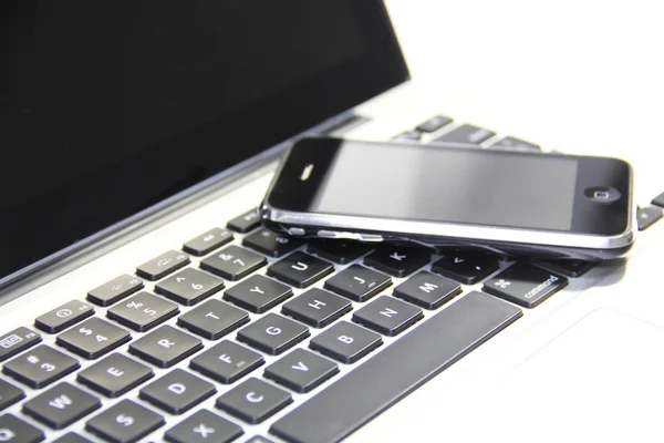 Telefone inteligente no teclado do laptop — Fotografia de Stock