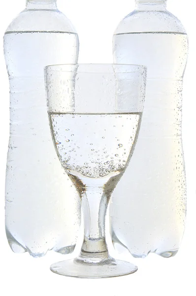 Água mineral em um copo e garrafas — Fotografia de Stock