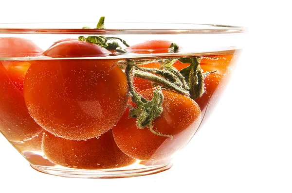 Tomates vermelhos em uma chapa com água — Fotografia de Stock