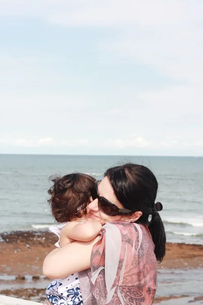 Mãe abraçando seu bebê sobre o mar — Fotografia de Stock