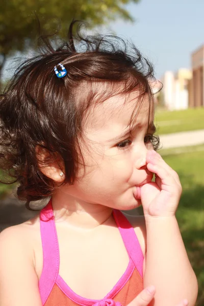 Lilla flicka, suger hennes tumme promenader i parken — Stockfoto