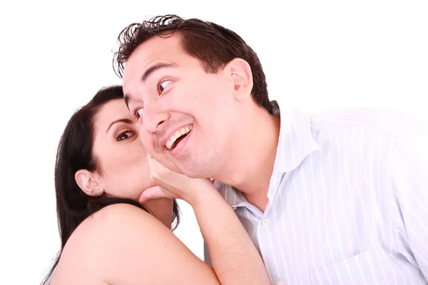 Pretty girl talking secret to young man in his ear, man smiling — Stock Photo, Image
