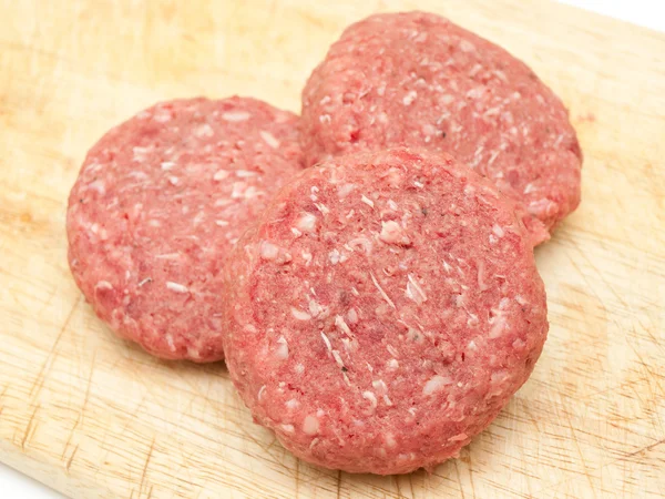 Las hamburguesas de carne cruda se cierran en una tabla Imágenes de stock libres de derechos