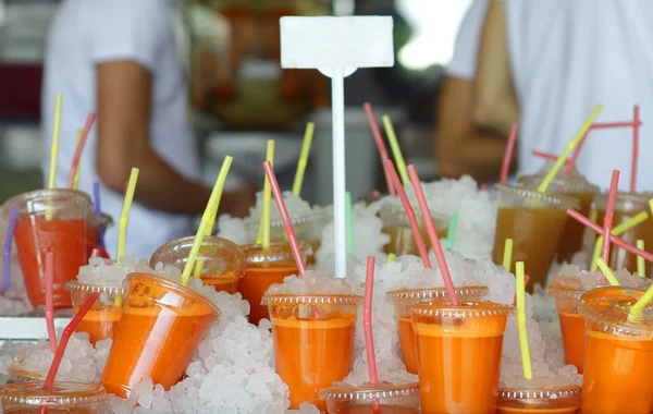 Πλαστικά ποτήρια με κρύο χυμό φρέσκο χυμό καρότο στο Τελ-Αβίβ αγορά Royalty Free Εικόνες Αρχείου