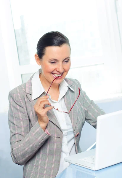 Smiling young business woman with glasses using laptop — Stock Photo, Image