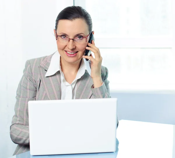Sonriente joven mujer de negocios con gafas usando el ordenador portátil —  Fotos de Stock