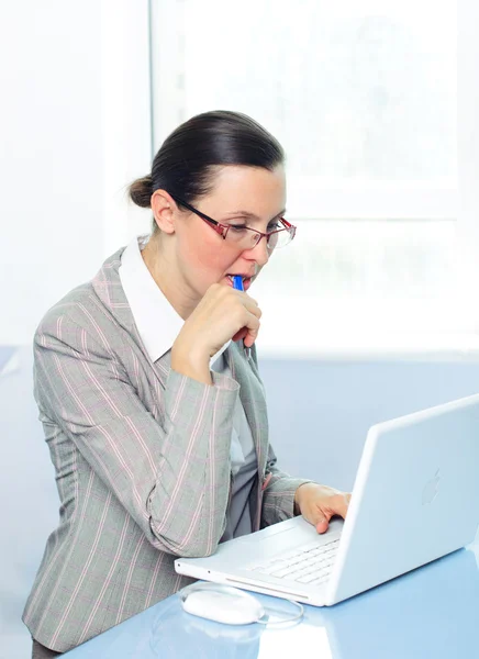 Sorrindo jovem mulher de negócios com óculos usando laptop — Fotografia de Stock