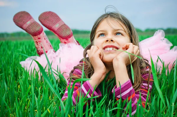 Egy gyönyörű kislány fekszik a fűben — Stock Fotó