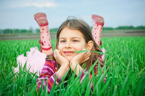 En vacker liten flicka liggande i gräset — Stockfoto