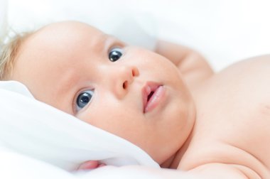 Beautiful baby girl is lying in a bed. clipart