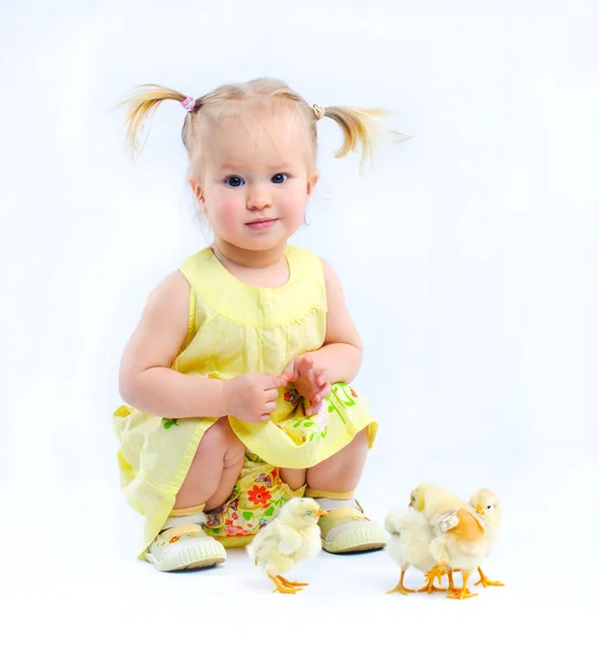 Cute little girl in a yellow dress with really live chickens. — Stock Photo, Image