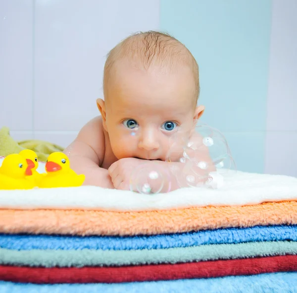 Malý roztomilý chlapec s mýdlovými bublinami na barevné ručníky — Stock fotografie