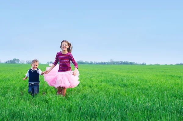 Sister runing with her brather on the grass — Stock Photo, Image