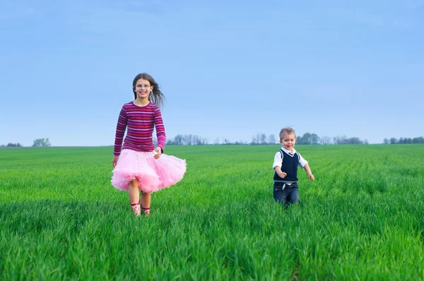 Sister runing with her brather on the grass — Stock Photo, Image